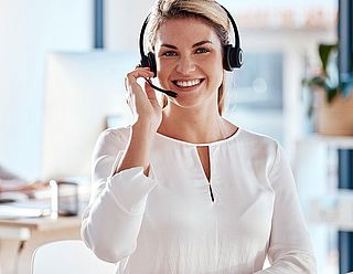 Freundlich lächelnde Beraterin im Kundencenter mit Headset
