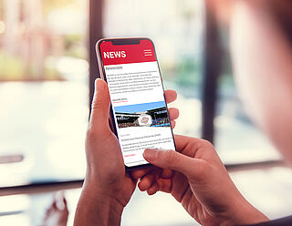 Frau hält Handy in der Hand und liest Nachrichten aus dem DEURAG Newsroom