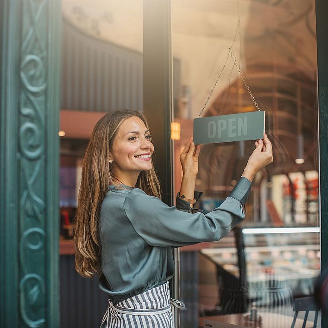 Selbstständige Unternehmerin dreht das OPEN-Schild an ihrem Laden, um den Arbeitstag zu beginnen