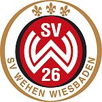 Logo SV Wehen Wiesbaden Rundes Vereinslogo in Rot, Weiß, Schwarz und Gold: Auf rotem Grund in einem schwarzen Ring die weißen Buchstaben „SV“ oben, darunter stilisiert überlappend ein großes weißes „W“, und darunter die Zahl „26“. Der schwarze Innenring ist von einem goldenen Außenring umgeben. Im oberen Drittel des Außenrings sind drei goldene Lindenblätter angeordnet, unten steht in Großbuchstaben „SV WEHEN WIESBADEN“ in Gold.