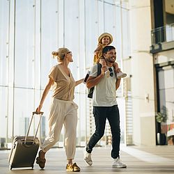 DEURAG Reiserechtsschutz Glückliche Familie im Flughafen auf dem Weg zu ihrer nächsten Reise