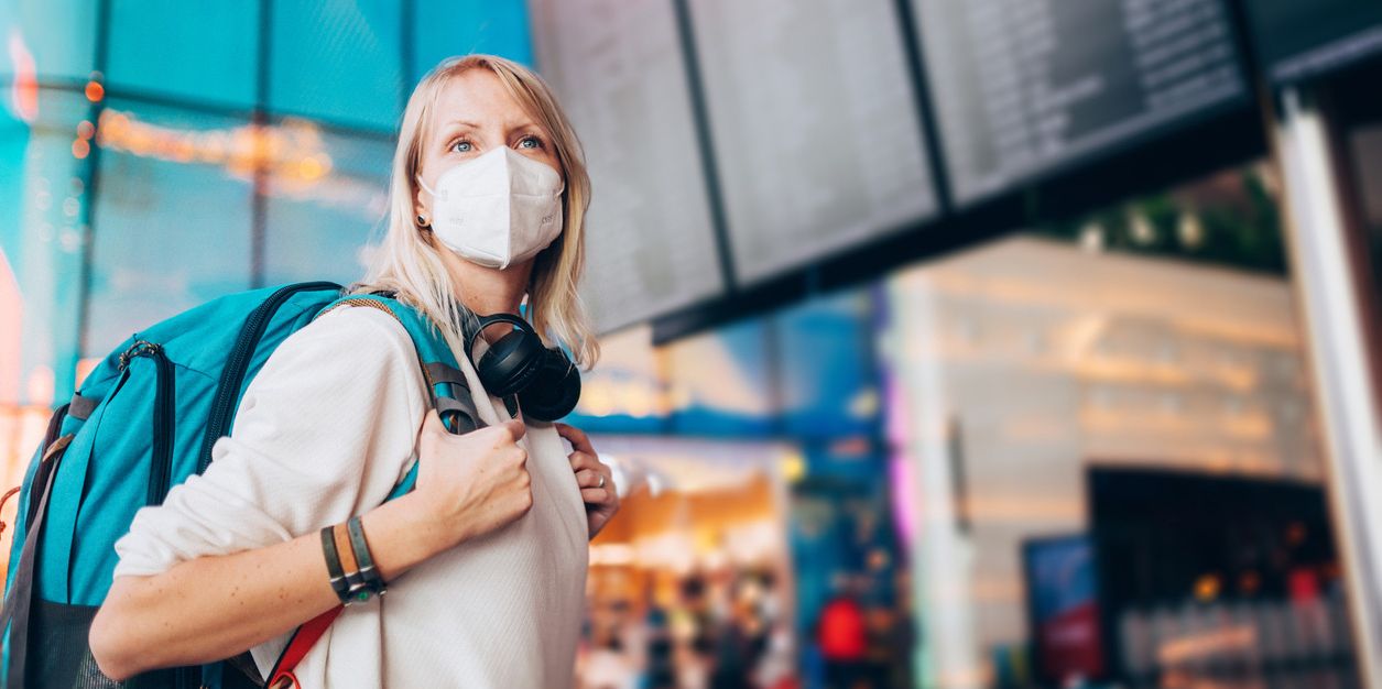 Pauschalreise und Corona: Frau mit Maske am Flughafen