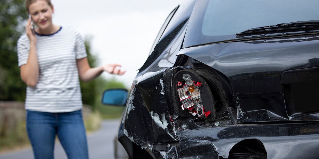 Frau telefoniert neben ihrem Auto nach einem Unfall