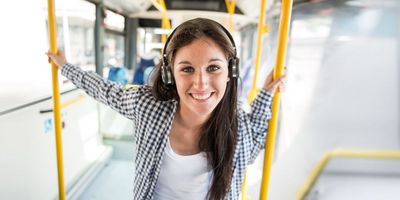 Azubis gesucht Lächelnde junge Frau mit Kopfhörern im Bus