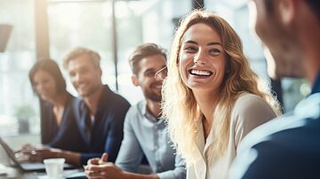 Glückliche Mitarbeitende sitzen am Tisch 