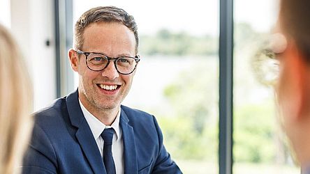 Lachender Versicherungsberater im Gespräch mit Kunden