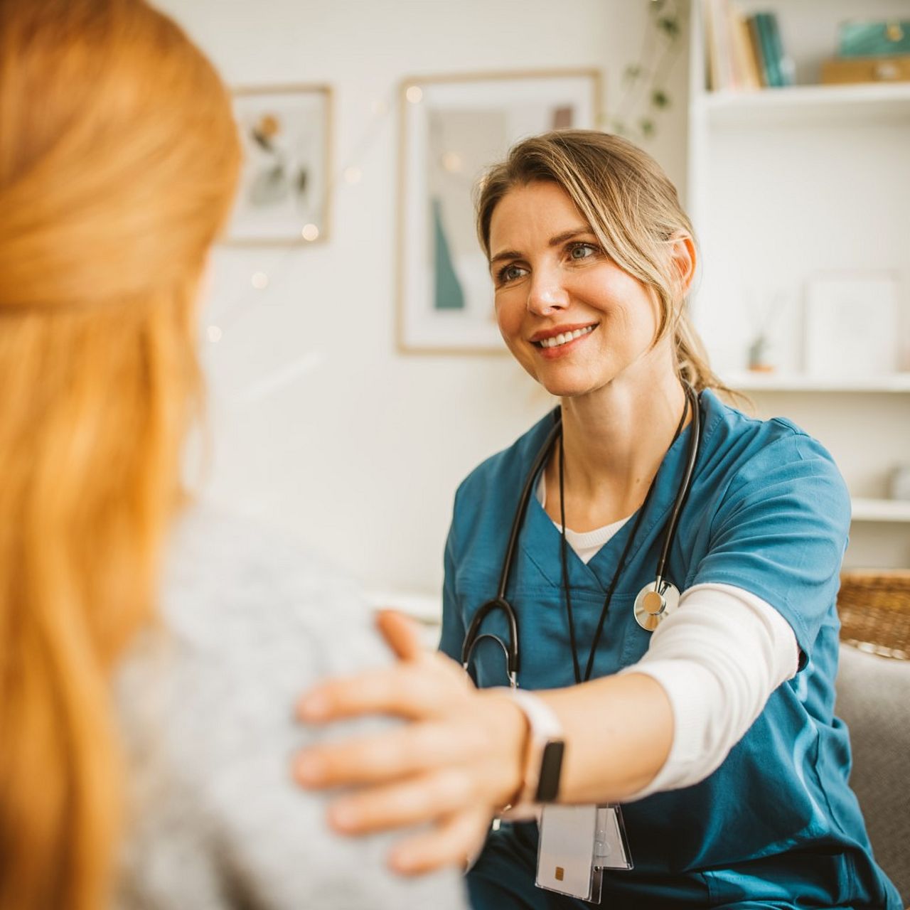 Freundliche Medizinerin legt eine Hand auf die Schulter der Patientin