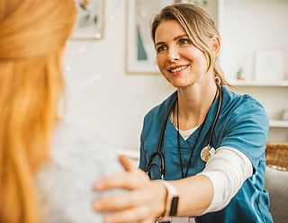 Freundliche Medizinerin legt eine Hand auf die Schulter der Patientin