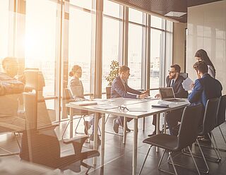 Besprechungsraum mit Beschäftigten im Gespräch sitzend an einem Besprechungstisch