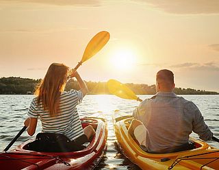 Päarchen in Kajak paddelt Richtung Sonnenuntergang