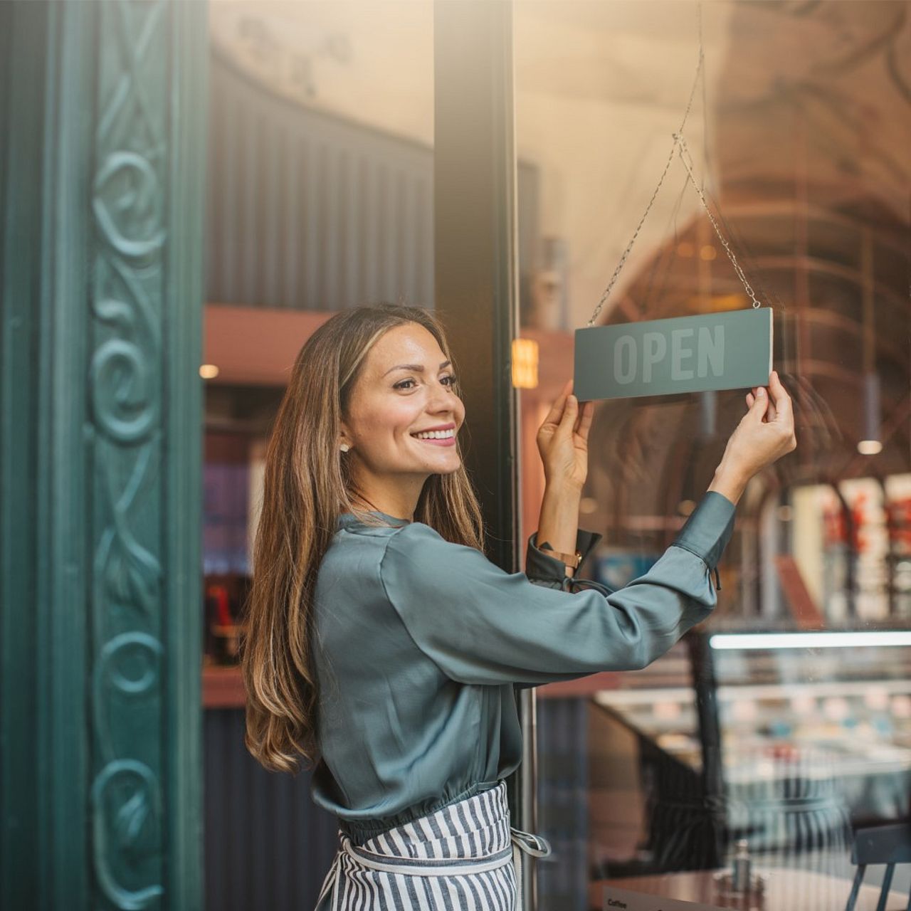 Selbstständige Unternehmerin dreht das OPEN-Schild an ihrem Laden, um den Arbeitstag zu beginnen