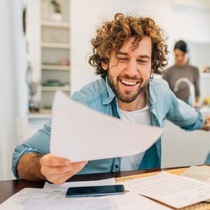 Selbstständiger sitzt am Tisch und hat vor sich Rechnungen liegen