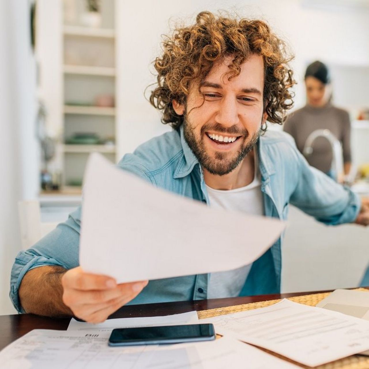 Service AnspruchPLUS - Forderungsmanagement Selbstständiger sitzt am Tisch und hat vor sich Rechnungen liegen