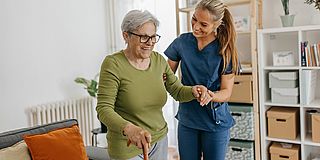 Jüngere Frau stützt Seniorin