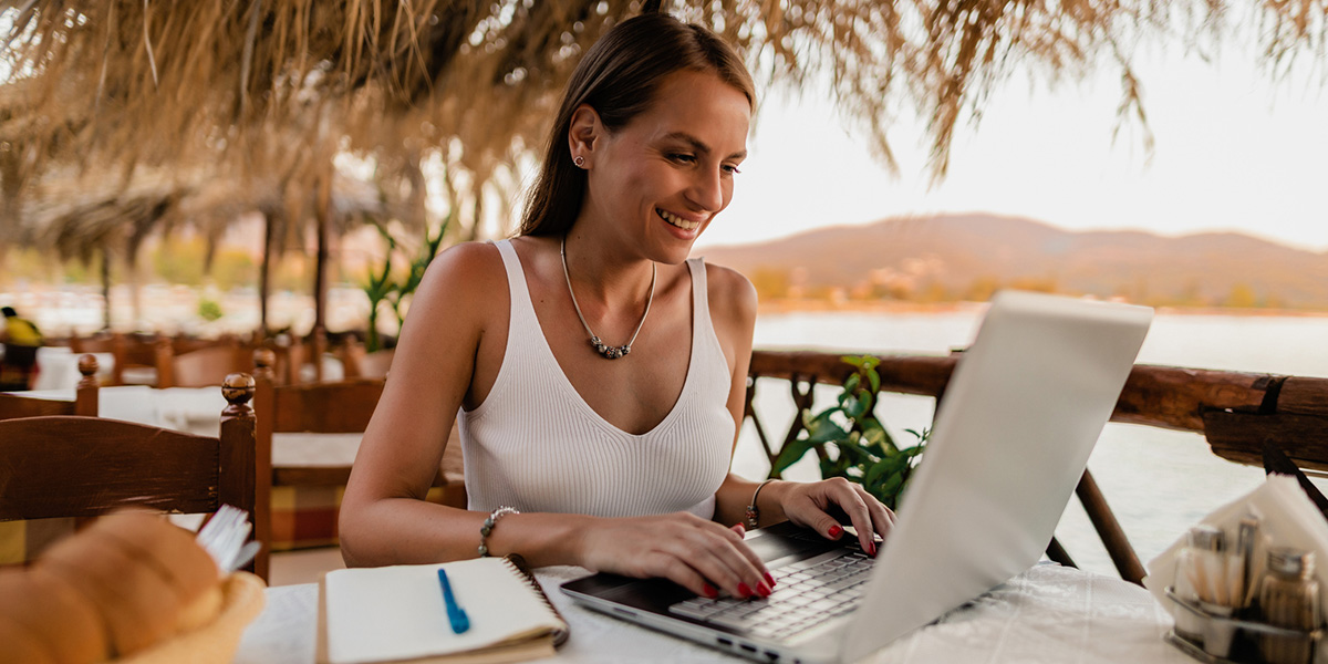 Arbeiten im Urlaub? Frau mit Laptop arbeitet in Urlaubsregion