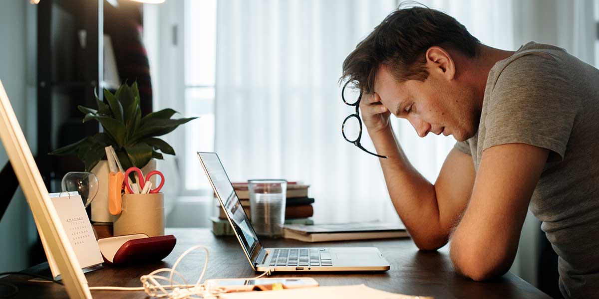 Arbeitgeber zahlt Lohn nicht - verzweifelter Mann am Schreibtisch