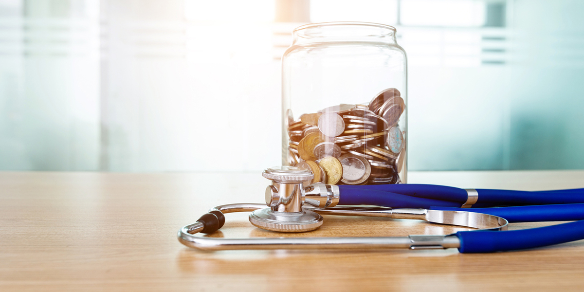 Pflegekosten steuerlich absetzen: Ein Glas zum Sparen steht neben einem Stethoskop