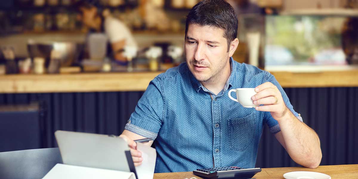 Mann sitzt im Café am Laptop