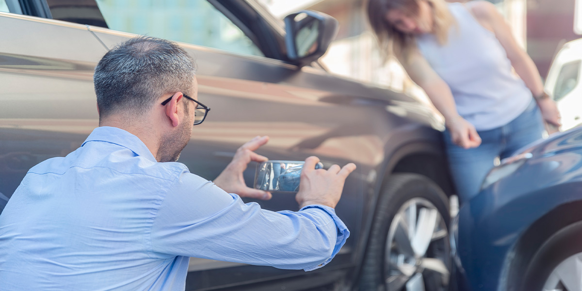 Haftung bei Carsharing-Unfall Mann fotografiert Schaden bei Carsharing-Unfall