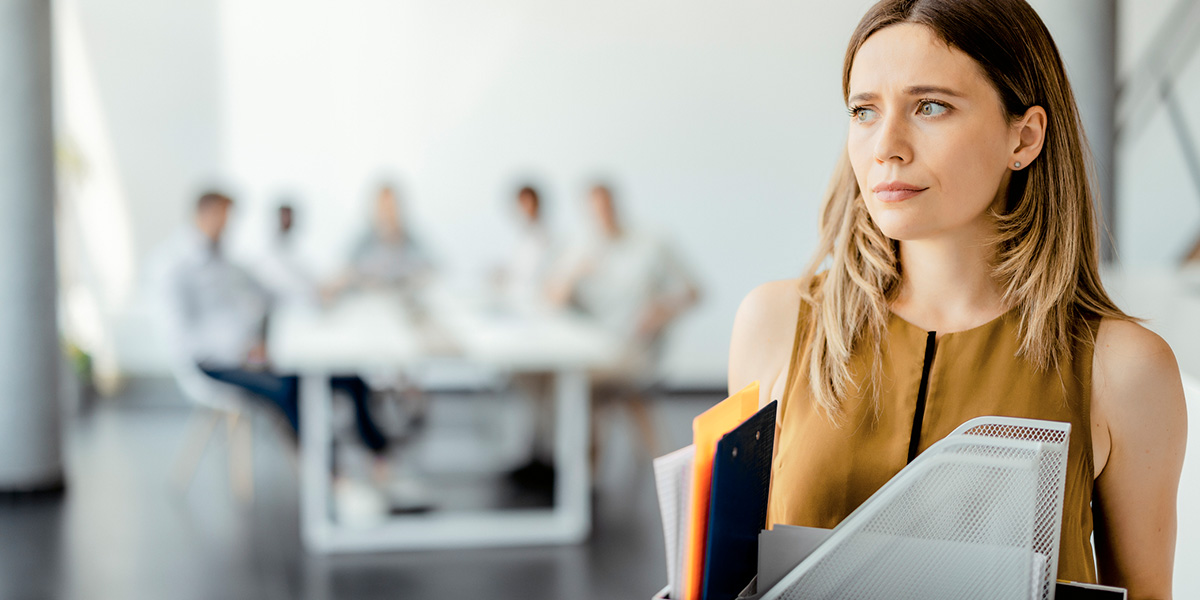 Sozialauswahl bei Kündigung Frau verlässt ihren Schreibtisch mit Büromaterial im Arm