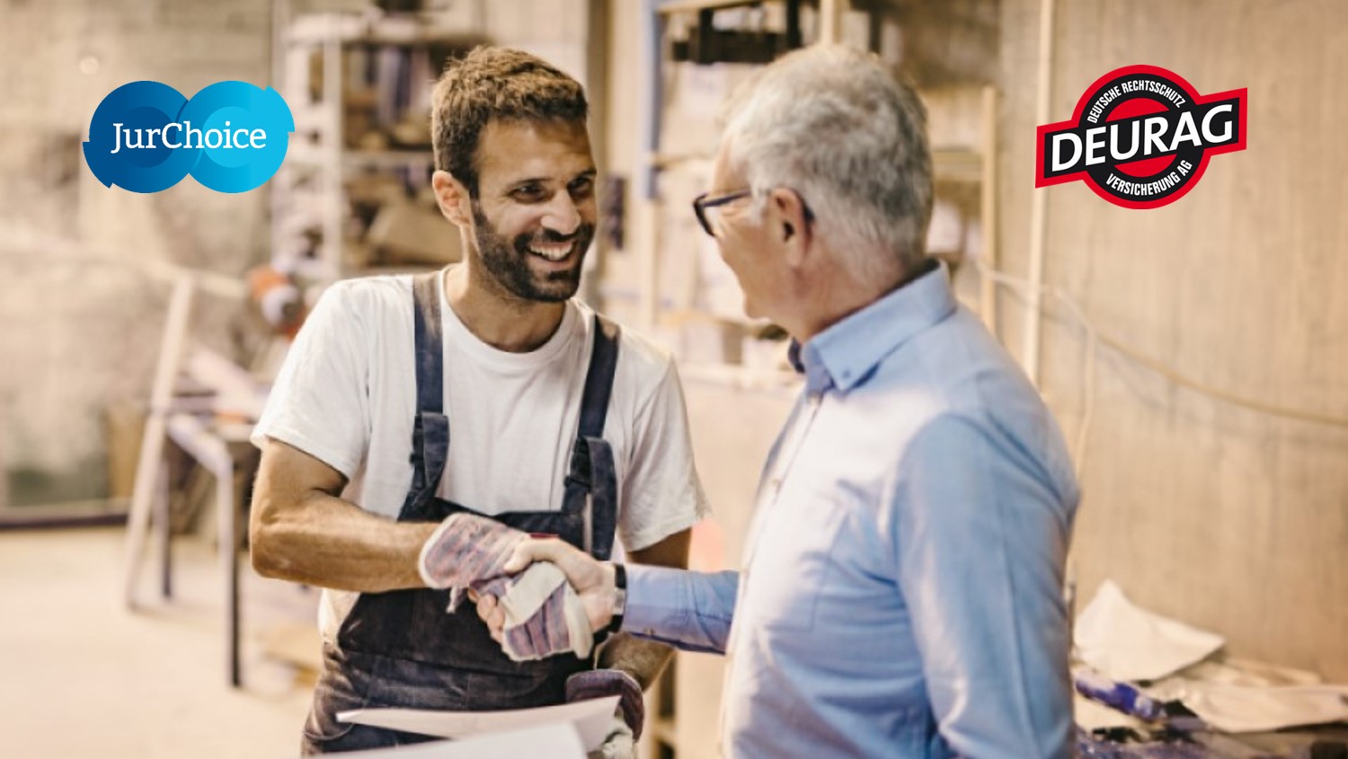 Handwerker und Kunde schütteln sich lächelnd in einer Werkstatt die Hand.