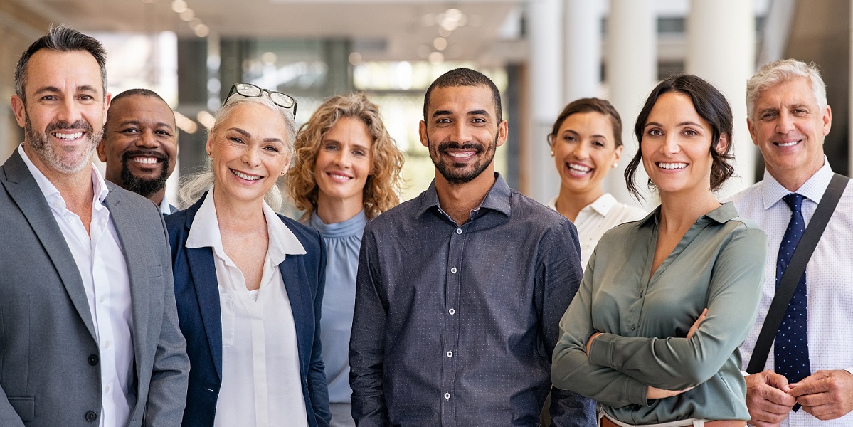 Menschen im Business-Kontext unterschiedlichen Alters und Herkunft lächeln in die Kamera.